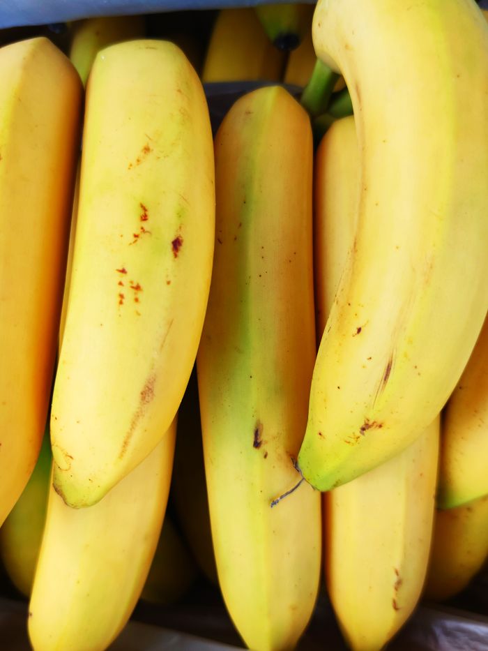 who-we-are A vibrant close-up of fresh ripe bananas stacked in a vertical arrangement, showcasing their bright yellow color.